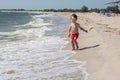 A small child runs along the seashore afraid of wave hair develop in the wind,