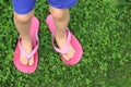 A small child`s barefeet in flip-flops of an adult standing on the lawn