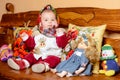 A small child in a shawl sitting on a sofa with embroidered pillows Royalty Free Stock Photo