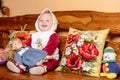 A small child in a shawl sitting on a sofa with embroidered pillows Royalty Free Stock Photo