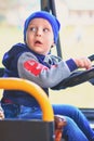 A small child sits in the cab of the bus behind the wheel and looks back. Vertical portrait Royalty Free Stock Photo