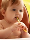 small child sits on a chair and eating with spoon. little smiling girl sits in baby-chair and have a breakfast