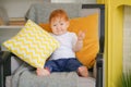 Small child sits in a chair and holds a pillow in his hands.