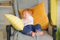 Small child sits in a chair and holds a pillow in his hands.