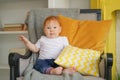 Small child sits in a chair and holds a pillow in his hands.