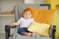 Small child sits in a chair and holds a pillow in his hands.