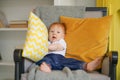 Small child sits in a chair and holds a pillow in his hands.