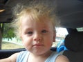 A small child sits in the driver`s seat instead of his father, proudly looking forward. A well-fed boy with blond fluffy long- Royalty Free Stock Photo