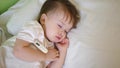 Small child sleeps in hospital ward on white bedding and measures temperature with thermometer. Treatment of children in Royalty Free Stock Photo