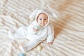 small child smiling baby in a white bunny rabbit costume easter playing with colorful easter eggs Royalty Free Stock Photo