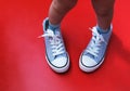 A small child in the sneakers of a large adult. the concept of growing up, the continuity of generations, parental care.
