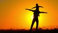 A small child spinning on his father`s shoulders. Happy family playing at sunset. Silhouette.