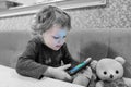 A small child of three years old sits with a phone in his hands at home. The concept of children`s addiction to gadgets, home leis Royalty Free Stock Photo