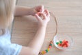 Small child, toddler stringing colored plastic beads on string, kid`s fingers close-up, concept of development of fine motor Royalty Free Stock Photo