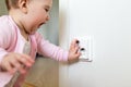 Small child touches an electrical outlet at home. Safety of children