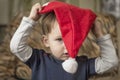 A small child is trying to put on a Santa Claus hat