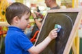 Small child wipes the chalk board. Royalty Free Stock Photo