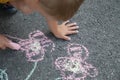 A small child in a yellow t-shirt draws chalk colored flowers on