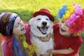 Small children dressed in elegant festive fun wigs with their dog