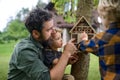 Small children with father holding bug and insect hotel in garden, sustainable lifestyle. Royalty Free Stock Photo