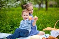 Small children have lunch in the open air. Children with a picnic basket in the spring garden with blooming Apple trees and Royalty Free Stock Photo