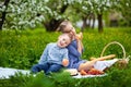Small children have lunch in the open air. Children with a picnic basket in the spring garden with blooming Apple trees and Royalty Free Stock Photo