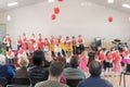 Small children in kindergarten dance on stage in front of their parents. Mom removing the performance of children on the