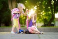 Small children learning to ride scooters in a city park on sunny summer evening. Cute little girls riding rollers. Royalty Free Stock Photo