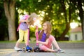 Small children learning to ride scooters in a city park on sunny summer evening. Cute little girls riding rollers. Royalty Free Stock Photo