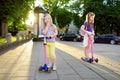 Small children learning to ride scooters in a city park on sunny summer evening. Cute little girls riding rollers. Royalty Free Stock Photo