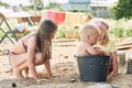 Small children play in the sand in the yard of their house in the summer.