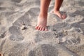 Small children`s feet on the sandy beach in summer.