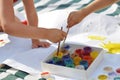 Small children`s hands paint with paints and brushes on a large sheet on the street on a Sunny day, creativity and fun Royalty Free Stock Photo