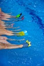 small children sitting on edge of pool and chatting with their feet in the blue warm water, Side view