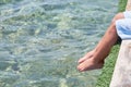 Small children sitting on the wooden pier in the water and enjoying summer day. Bare feet of boy. Vacation by the sea Royalty Free Stock Photo
