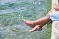 Small children sitting on the wooden pier in the water and enjoying summer day. Bare feet of boy. Vacation by the sea Royalty Free Stock Photo