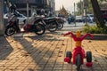 Small children tree-wheeled bicycle standing in front of motorbikes and scooters.