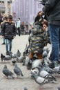 Small children on a winter day playing in a square in a European city. They enjoy chasing pigeons and feeding them Royalty Free Stock Photo