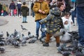 Small children on a winter day playing in a square in a European city. They enjoy chasing pigeons and feeding them Royalty Free Stock Photo