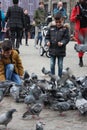 Small children on a winter day playing in a square in a European city. They enjoy chasing pigeons and feeding them Royalty Free Stock Photo