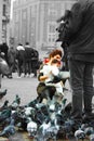 Small children on a winter day playing in a square in a European city. They enjoy chasing pigeons and feeding them Royalty Free Stock Photo