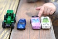 a small children& x27;s hand points to one toy car among a multitude of cars on a wooden red-yellow table Royalty Free Stock Photo