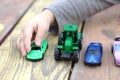 a small children& x27;s hand points to one toy car among a multitude of cars on a wooden red-yellow table Royalty Free Stock Photo