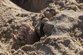 A Small childs feet sticking out the beach sand Royalty Free Stock Photo