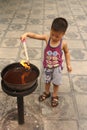 Small Chinese boy is burning incense in temple