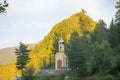 A small Christian chapel stands on the shore of forest lake.