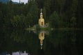 A small Christian chapel stands on the shore of forest lake.