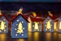 Small Christmas houses with Christmas tree windows that glow from the inside. Christmas garland in the form of houses with illumin