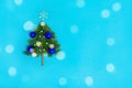 Small Christmas tree with blue balls on lturquoise background decorated by christmas lights with bokeh Royalty Free Stock Photo