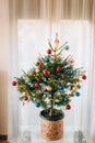 A small Christmas tree in a pot, decorated with balls, garlands Royalty Free Stock Photo